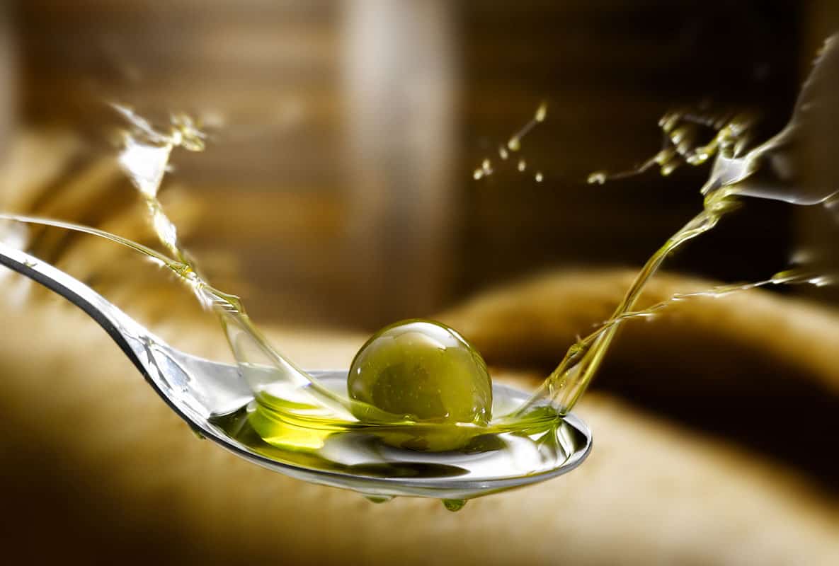 close up of olive oil splasing on a spoon